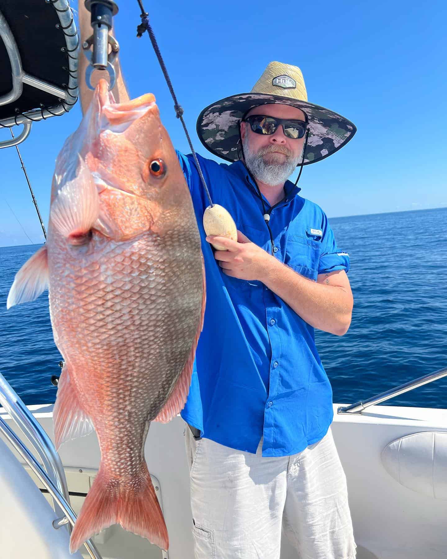 Man holding up a red snapper he caught while on a fishing charter in the Gulf of Mexico.