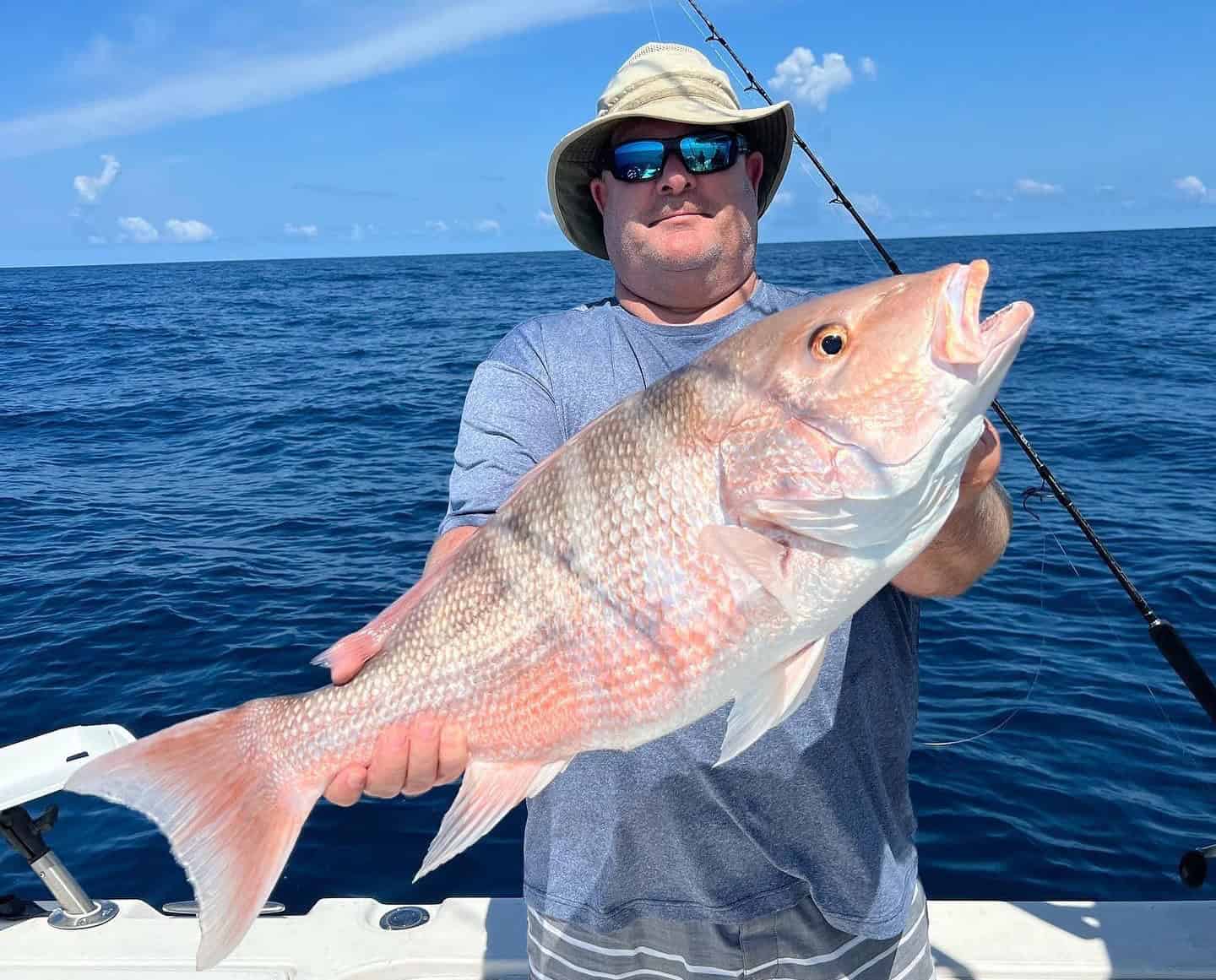 Man holding up a red snapper he caught while on a fishing charter in the Gulf of Mexico.