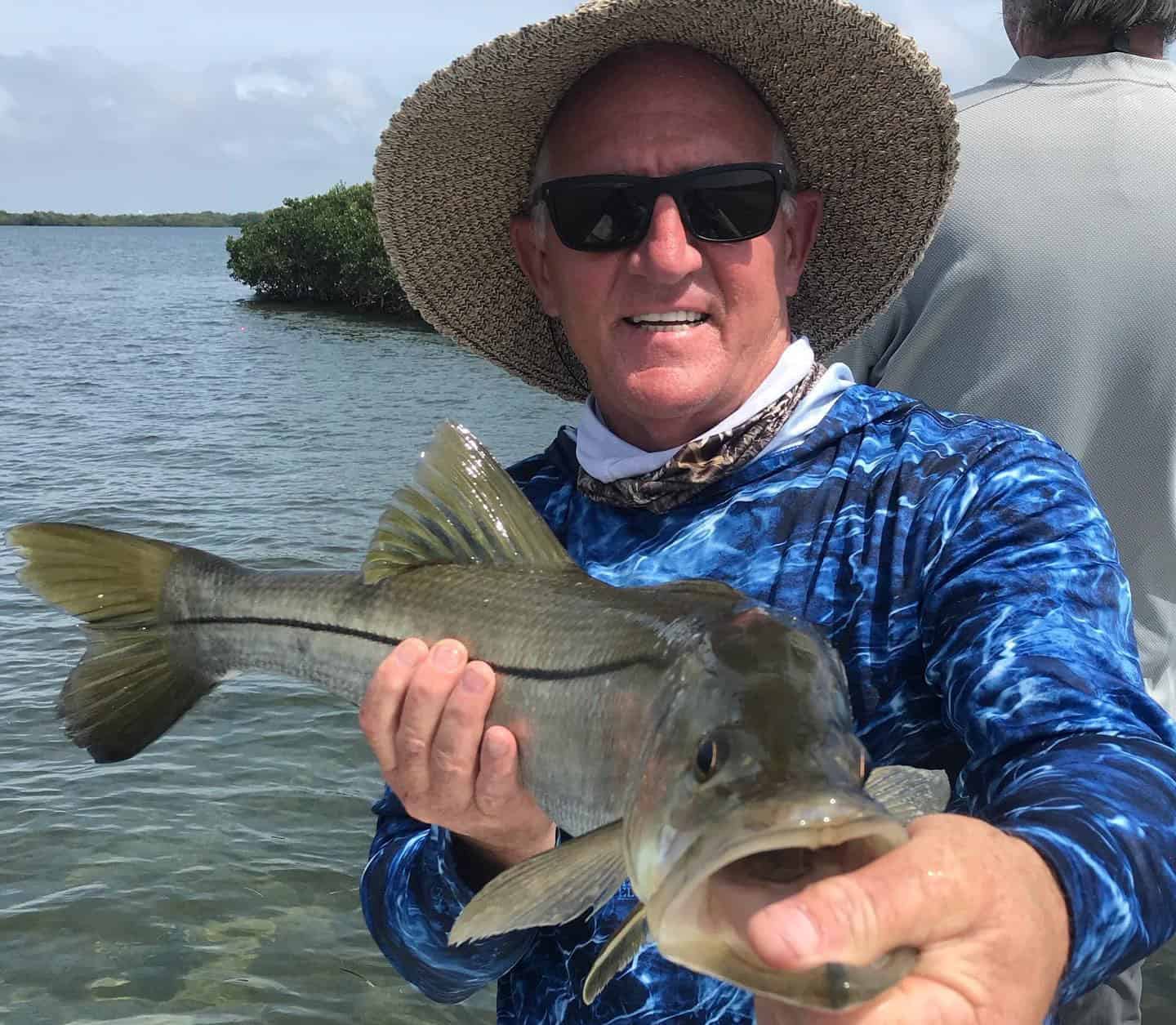 Man showing off a Snook caught while on a fishing charter boat in Florida.