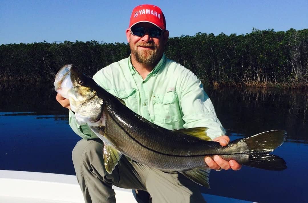 Fishing charter captain holding up a Snook he caught during an inshore fishing trip.