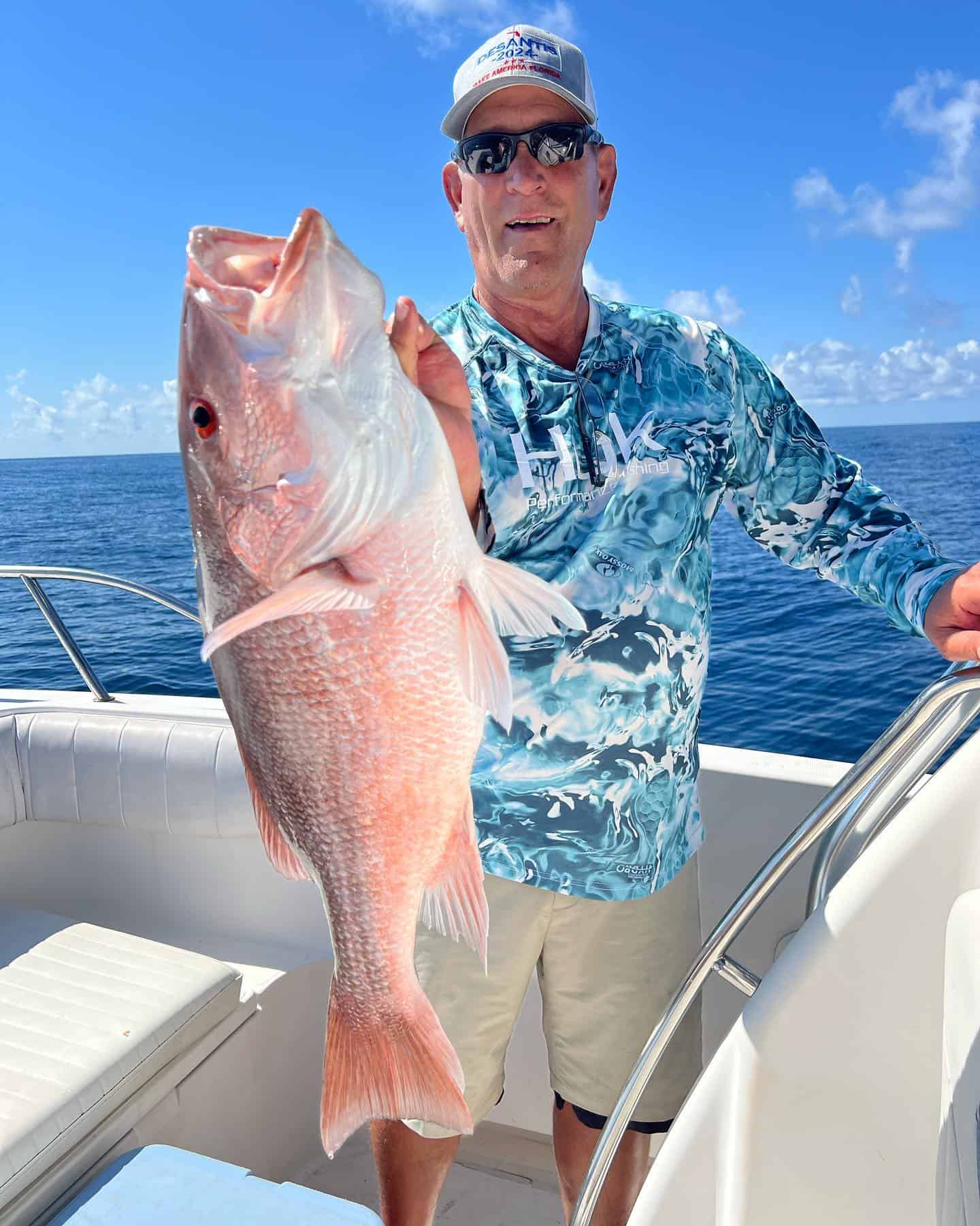 Man holding a red snapper on a fishing charter boat.
