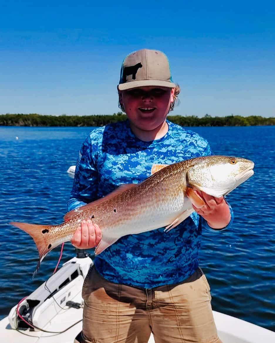 Boy holding up a redfish he caught while spring fishing in Crystal River, FL.