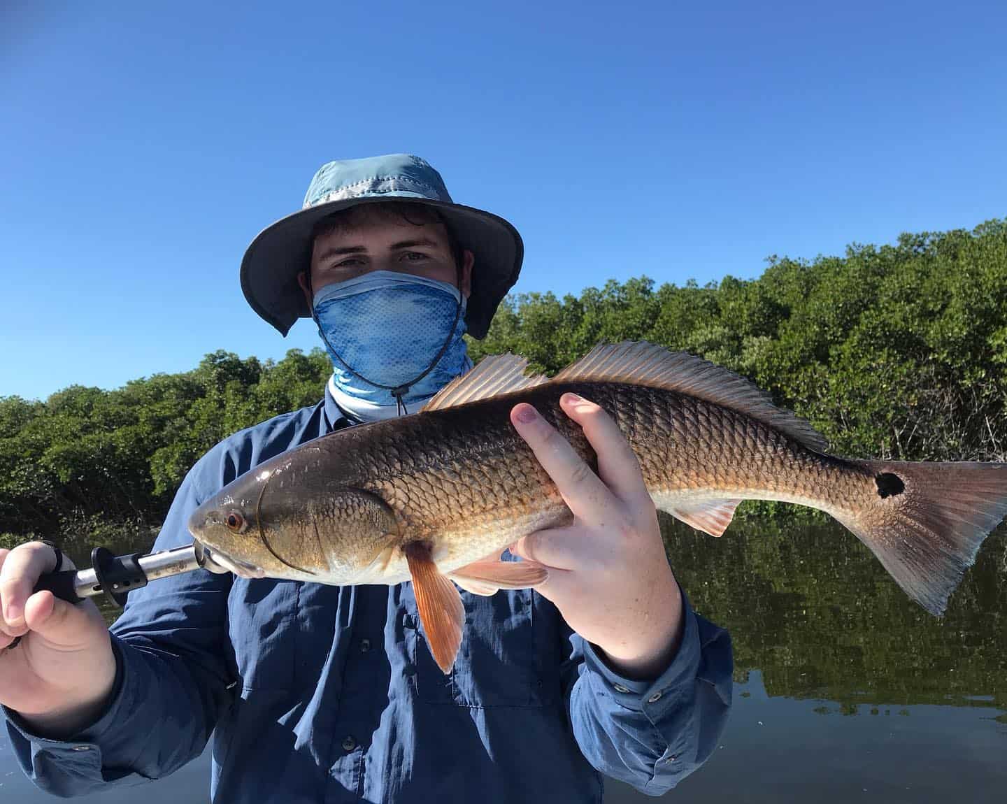 Man holding up a redfish he caught while on the water in Crystal River, FL.