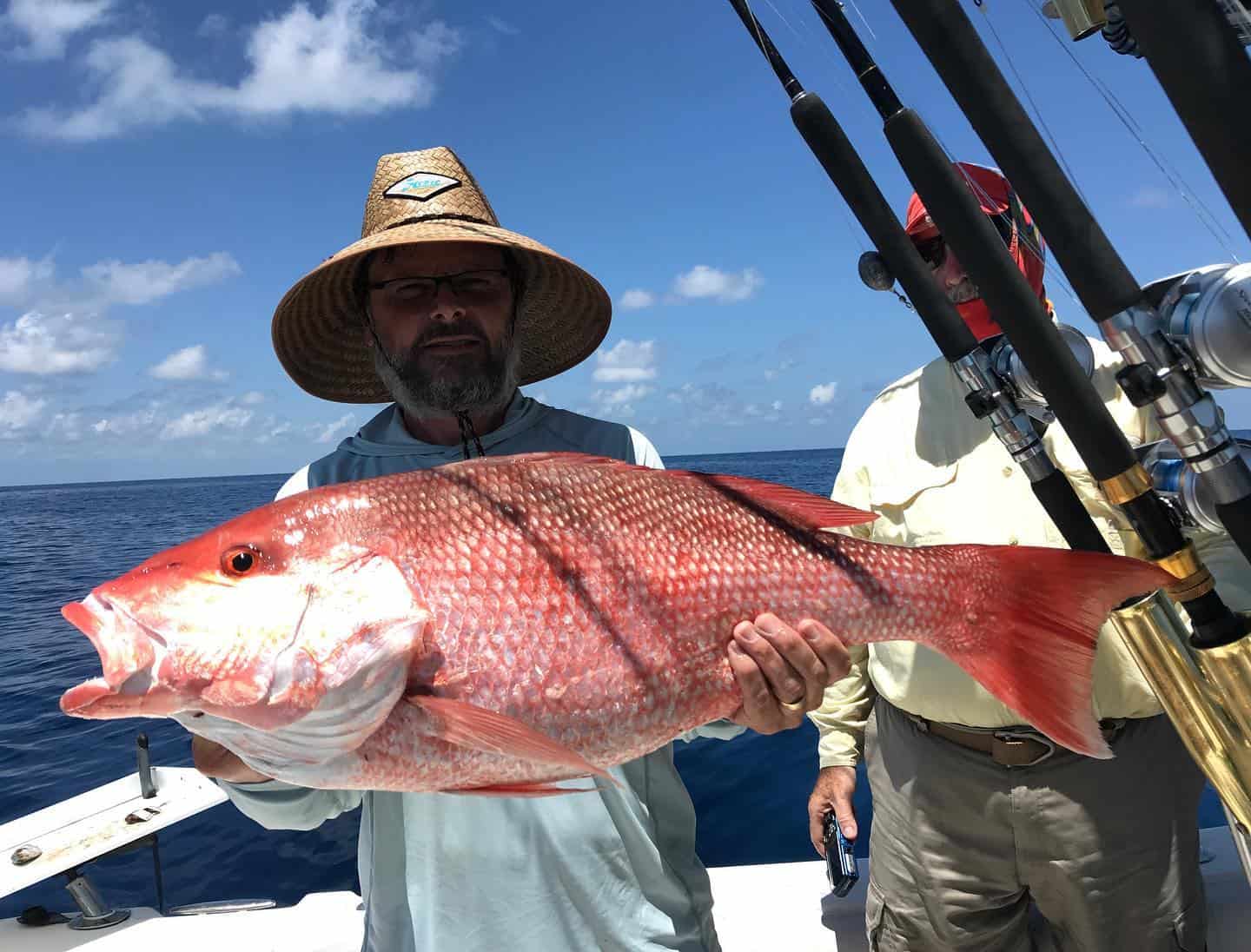 Angler holding a large red snapper on a fishing trip in Crystal River, FL, with a backdrop of clear blue skies and calm waters.