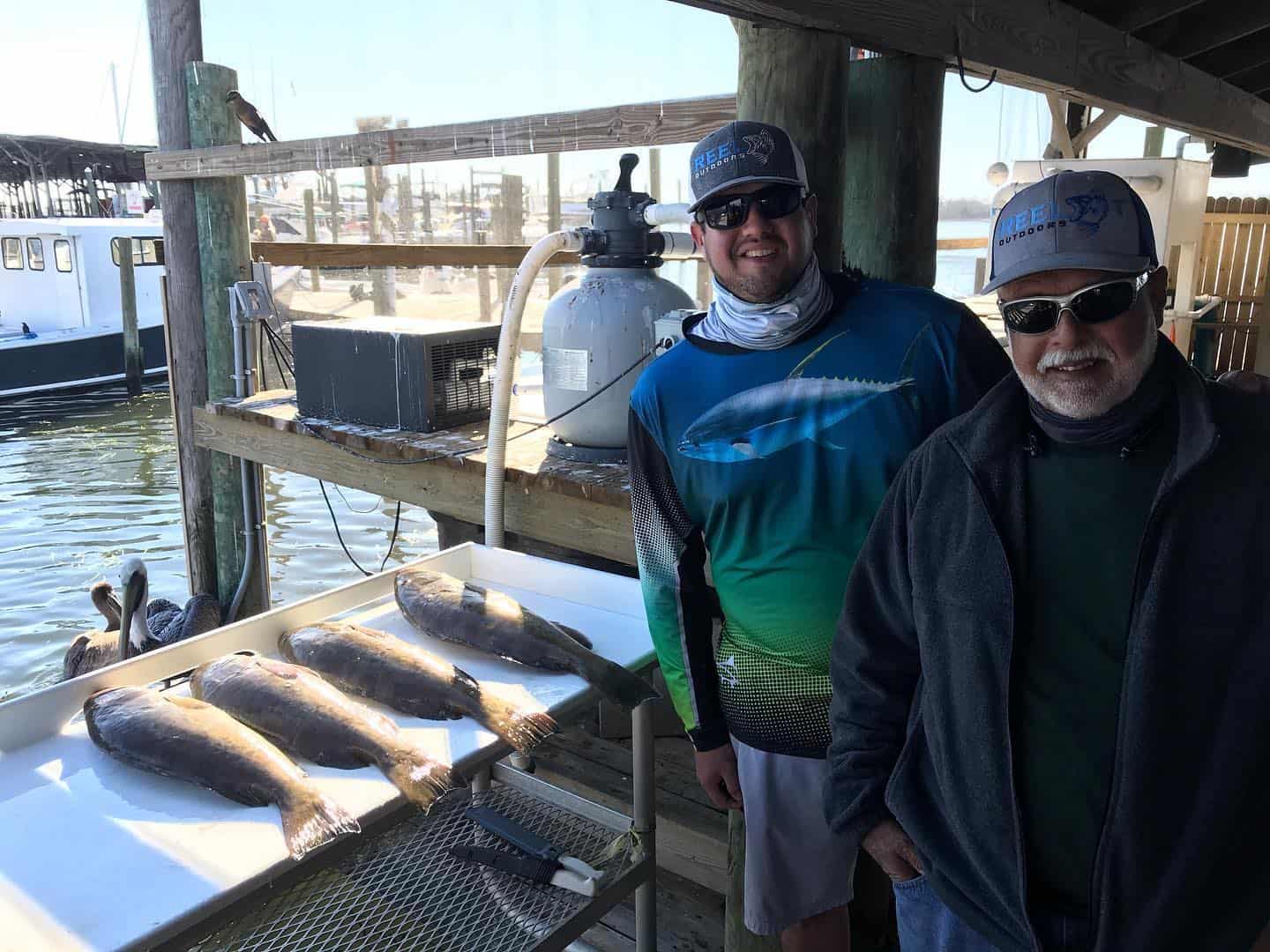 Two anglers with their fresh catch of grouper at a dockside cleaning station in Crystal River, FL, after a guided fishing trip with Salt River Outfitters.